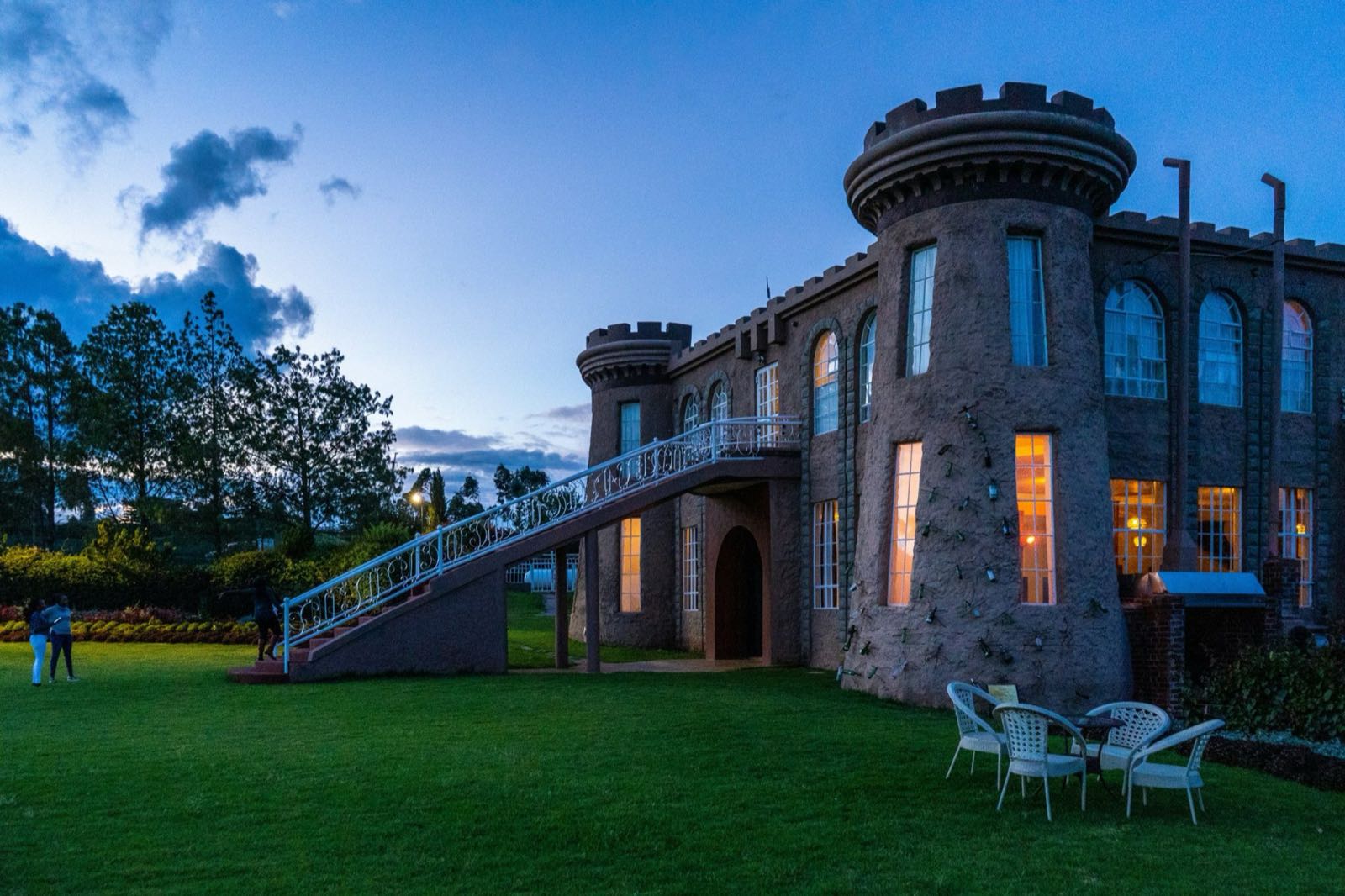 A stone country house with turrets, lit up at dusk